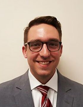 Portrait of a smiling man in glasses and a suit.