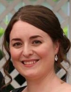 Smiling woman with dark hair and earrings.