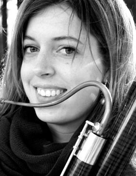 A smiling woman holding a bassoon, black and white portrait.