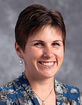 Smiling woman with short hair and earrings.