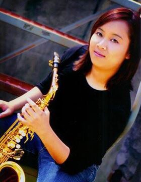 Woman holding a saxophone and smiling.