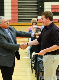 Two men shaking hands in a gymnasium setting.
