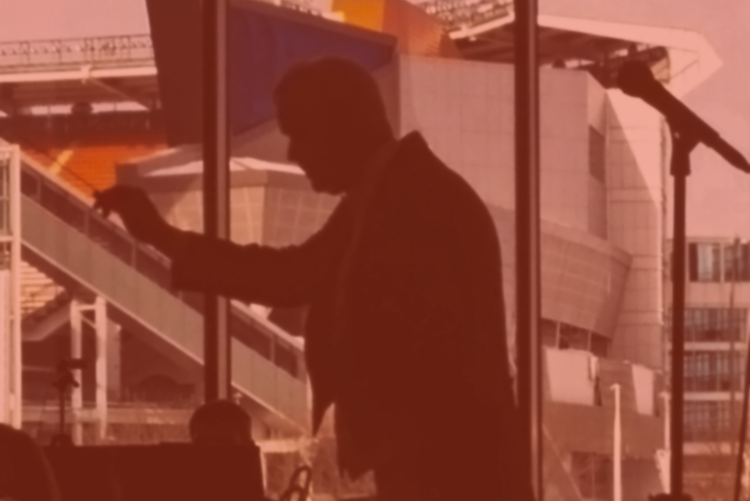 Silhouette of a man speaking indoors with a large window background.
