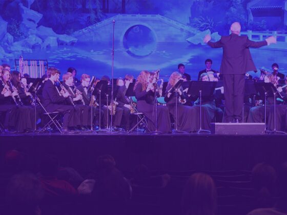 An orchestra performing on stage under blue lighting.