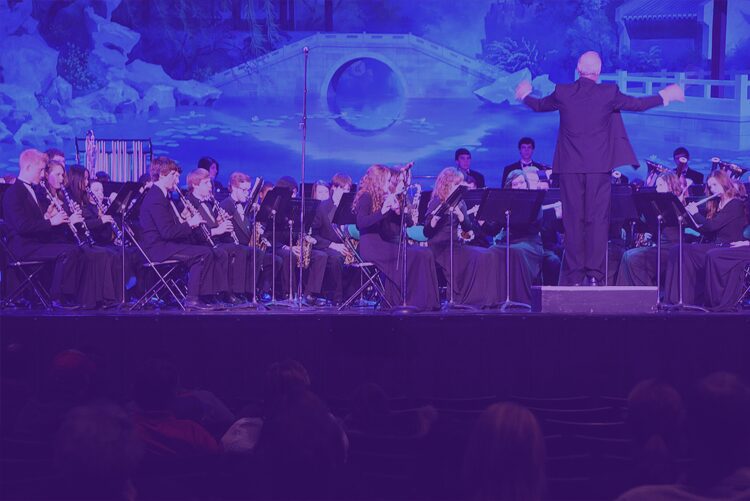 An orchestra performing on stage under blue lighting.