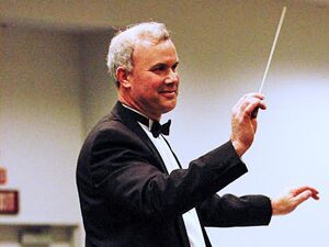 Conductor passionately leading an orchestra with a baton.