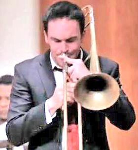 A focused man playing a trombone indoors.