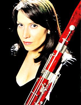 Woman posing with a bassoon against a black background.