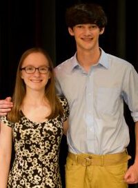 A smiling young woman and man posing together indoors.